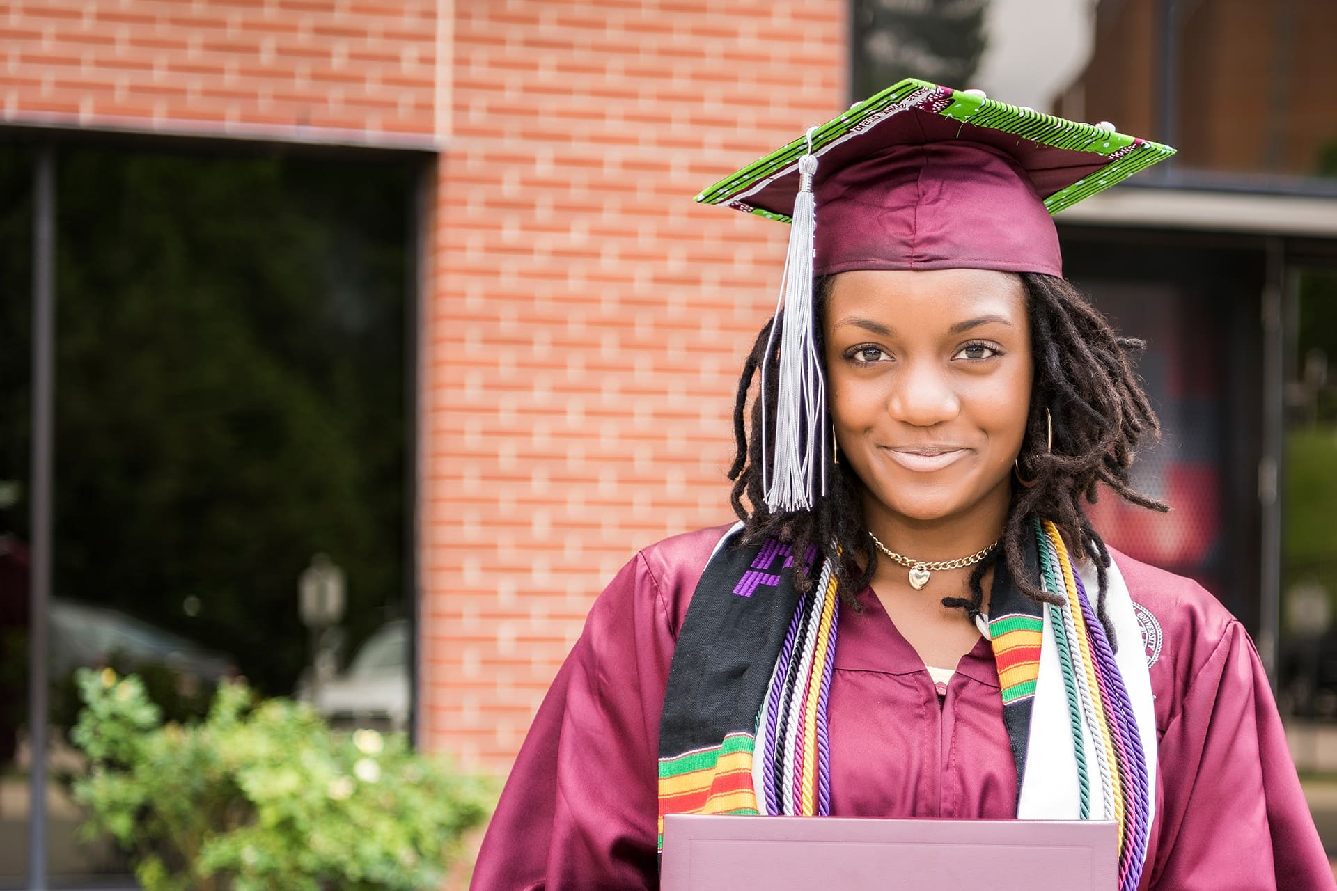 A young person in a graduation gown holding her diploma