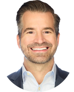 Headshot of a smiling man with a beard, wearing a navy blue blazer and light blue button-down shirt.