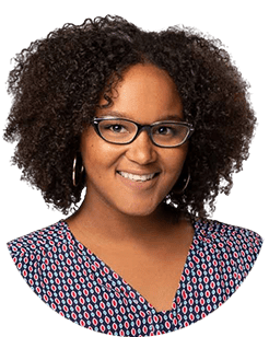 A woman with curly hair and glasses smiling.