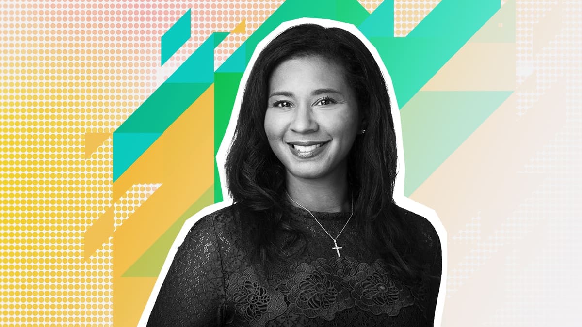 A woman is smiling in front of a colorful background.