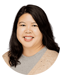 An asian woman smiling in a tan sweater.