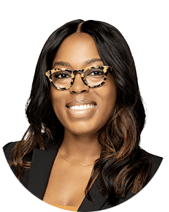 A black woman wearing glasses and a blazer.