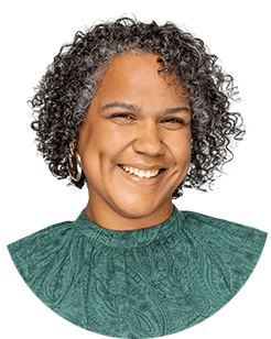 A smiling woman with curly hair wearing a green top.