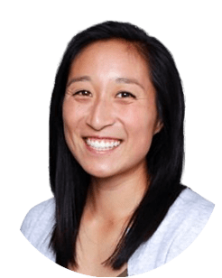 A person with dark hair and a light grey top, smiling at the camera against a white background.
