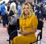 Sarah Blakely, founder of Spanx, sitting and smiling in a yellow dress