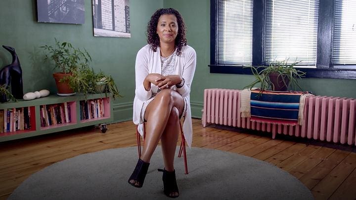 A woman sitting on a chair in a room with plants.