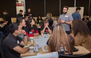 Braven Fellows sitting at a table, looking at and listening to their leadership coach