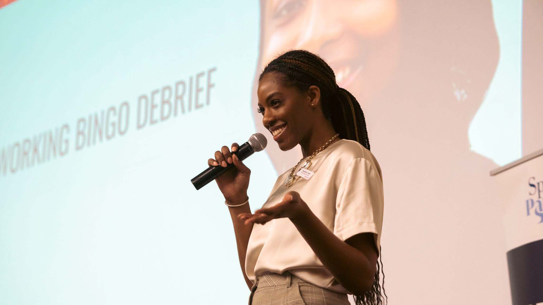 A woman is speaking into a microphone at an event.