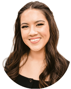 A woman with long brown hair and light makeup smiling, wearing a dark top.