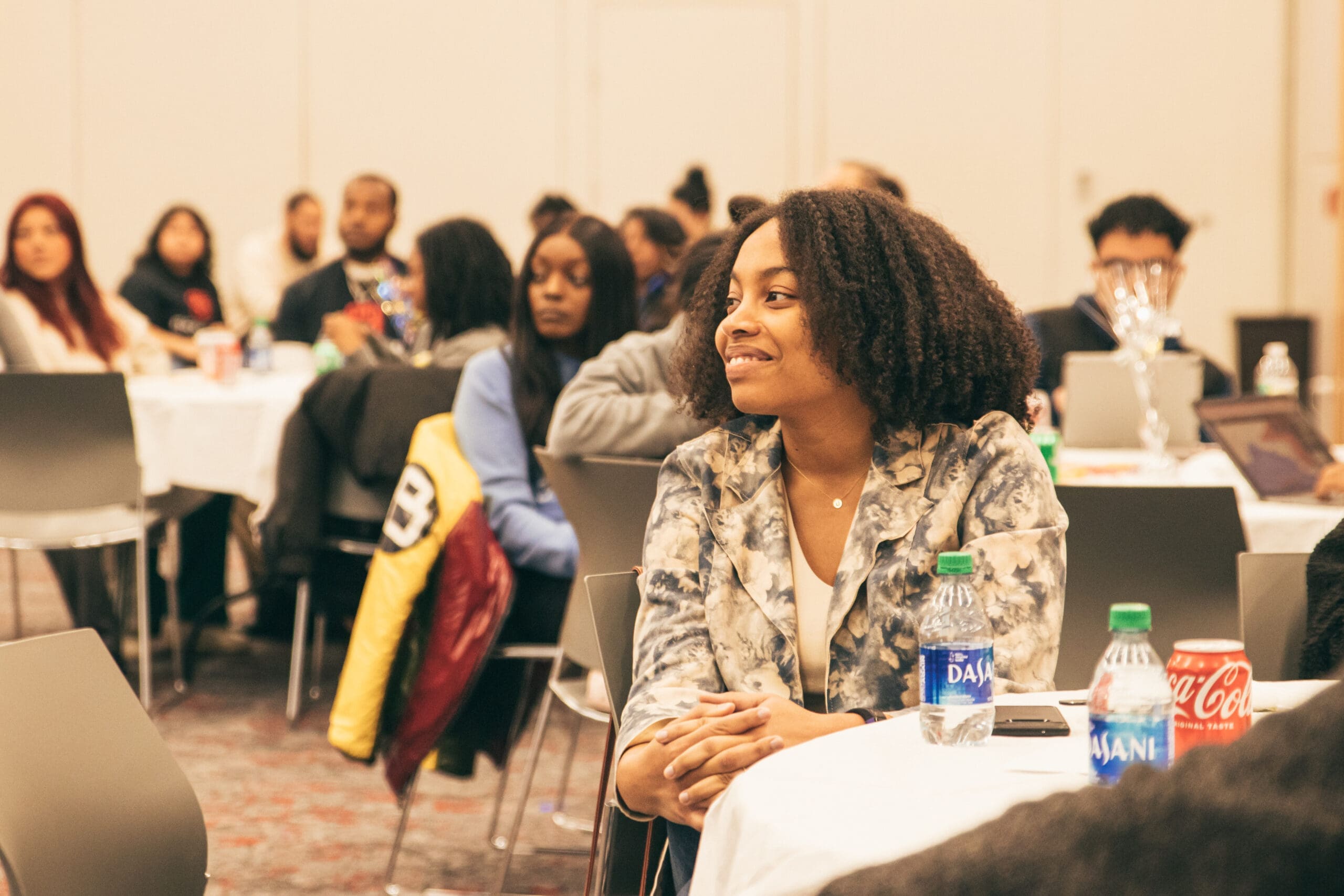A group of people sitting at tables in a conference room.