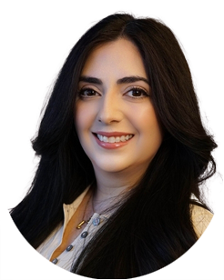 A woman with long dark hair and a light-colored top smiles at the camera against a plain background.