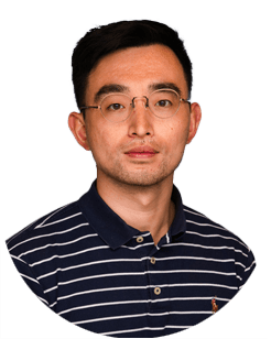 Man with short dark hair and glasses wearing a navy blue and white striped collared shirt, facing forward against a plain light background.