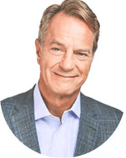Smiling man in a checked suit jacket and blue shirt on a white background.