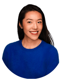Woman with long dark hair wearing a blue top, smiling and facing the camera against a plain light background.