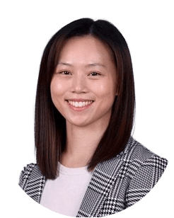 A smiling person with straight, shoulder-length hair, wearing a plaid blazer and white shirt, against a plain white background.