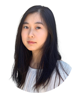 Young woman with long black hair and a neutral expression, wearing a white top, posed against a plain light background.