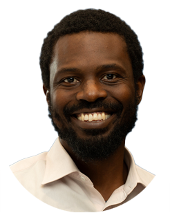 A man with short curly hair and a beard, wearing a light-colored collared shirt, smiling at the camera against a plain background.