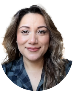 A woman with wavy brown hair and light makeup smiles at the camera, wearing a plaid shirt against a plain white background.
