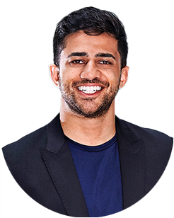 Smiling man with short dark hair and beard, wearing a navy shirt and black blazer, posed against a plain light background.