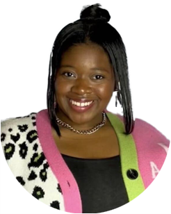 Woman smiling, wearing a black top, a colorful cardigan with pink and green sections, and a silver necklace, with straight black hair styled in a half-up bun.