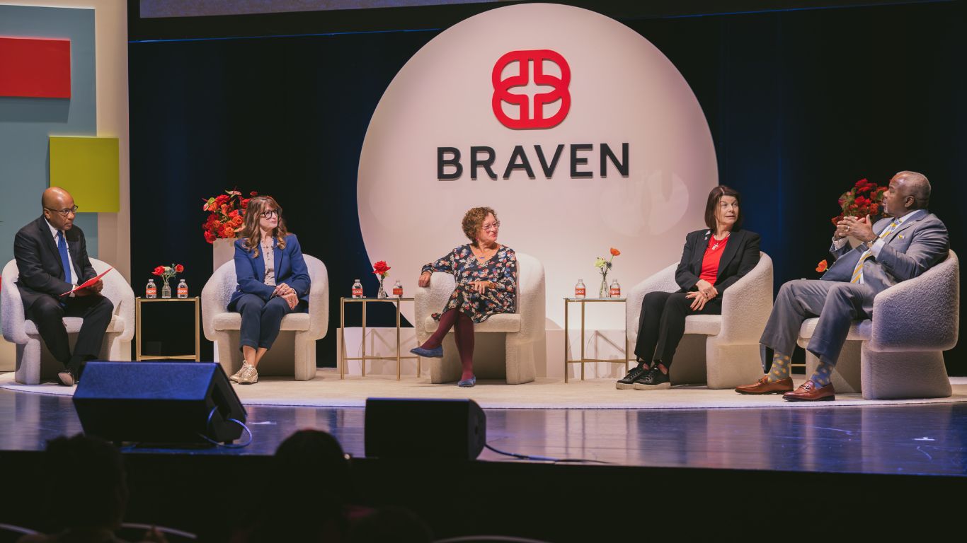 Five people sitting in armchairs on a stage during a panel discussion in front of a Braven logo.